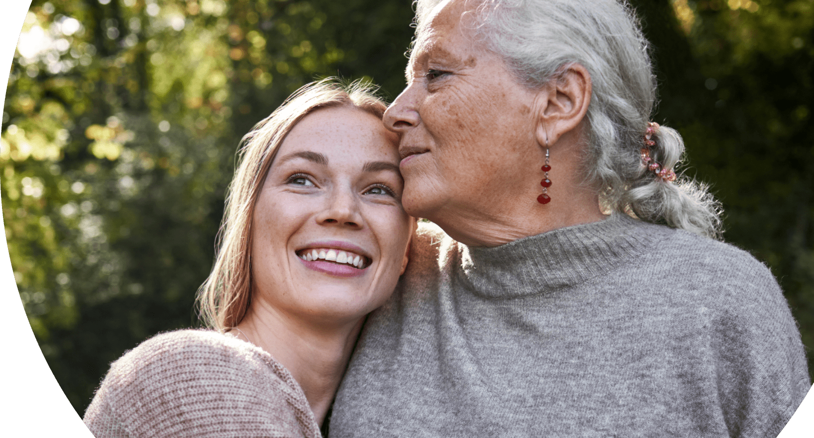 Adult daughter smiling and warmly embracing her elderly mother who lives with agitation in Alzheimer's dementia